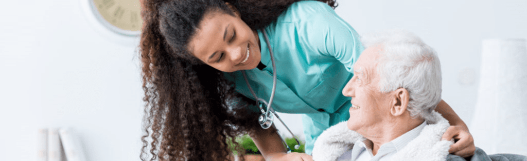 A registered nurse coming from a travel nurse recruitment program asks an elderly man how he‘s been feeling to see if she can do anything to make him feel more comfortable.