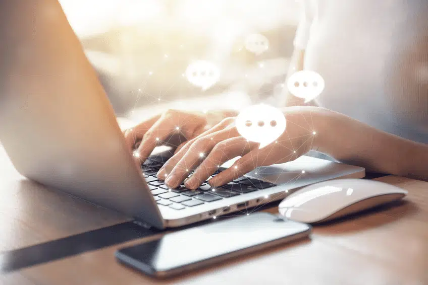 A businessperson is shown typing on their laptop with a customer service representative, utilizing live web chat to connect regarding pre-sales questions they have.