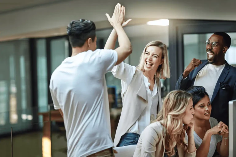 A company's employees hold a meeting to celebrate the recognition of success they've just received for completing a milestone in their current global customer service project by which they've been providing stellar multilingual customer support.